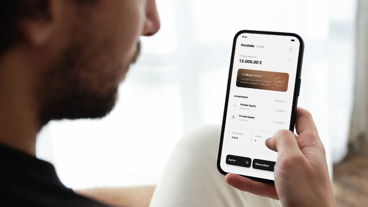 Una persona che tiene in mano uno smartphone e visualizza l'app Trade Republic Financial Portfolio, che mostra il saldo del conto, i dettagli dell'investimento e le opzioni di ricerca o personalizzazione nella parte inferiore dello schermo.
