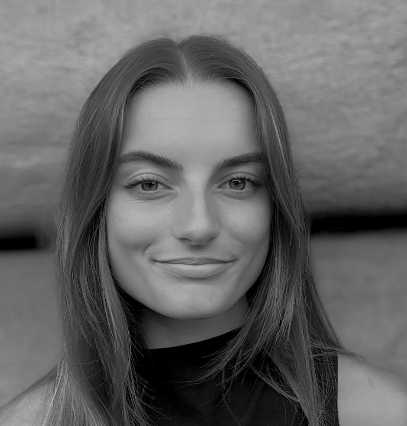 Ritratto in bianco e nero di Emilia Taddonio, giovane donna con capelli lunghi e lisci, che indossa un top senza maniche e guarda direttamente verso la macchina fotografica con un leggero sorriso e uno sfondo neutro.