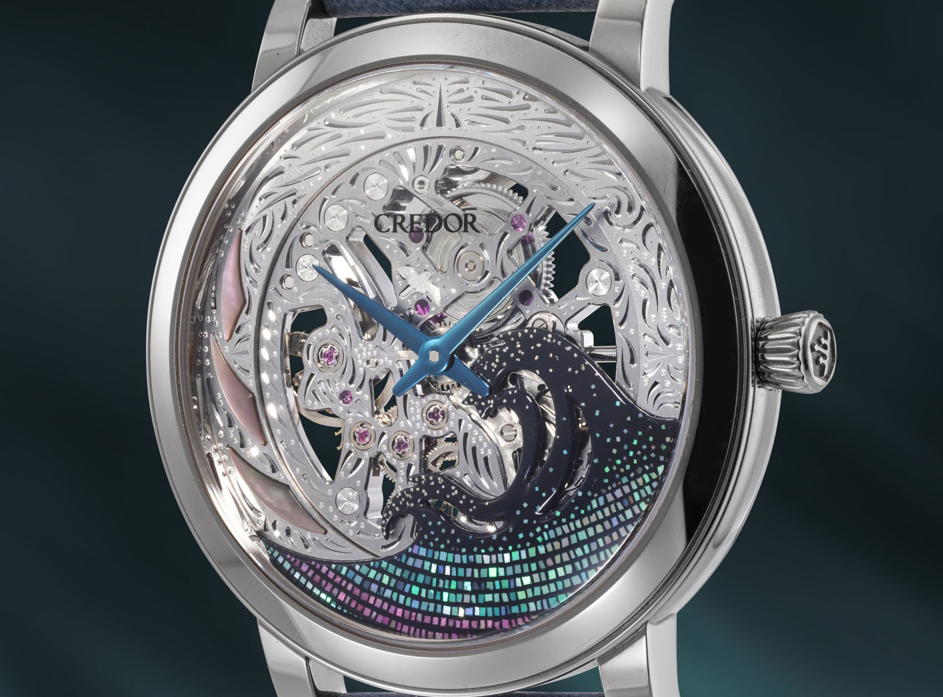 Un orologio da polso di lusso ispirato agli orologi giapponesi lusso, caratterizzato da un intricato quadrante traforato con design a onde oceaniche, tonalità metalliche blu e argento e lancette blu, elegantemente incastonato in una cassa in metallo lucido su sfondo scuro.