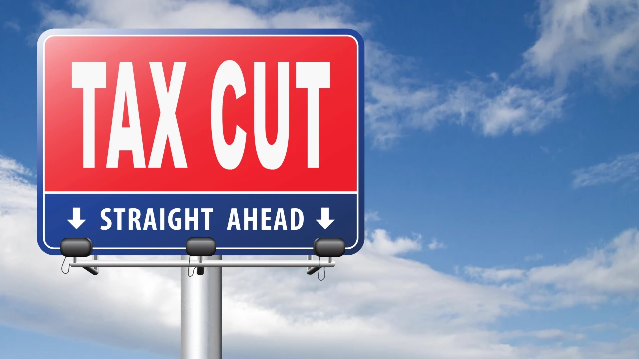 Un grande cartello stradale recita "TAX CUT" in grassetto a lettere bianche su sfondo rosso, con "STRAIGHT AHEAD" sotto in blu, con una freccia verso il basso - che allude ai benefici della rottamazione quinquies 2026 derivanti dalla legge di bilancio.