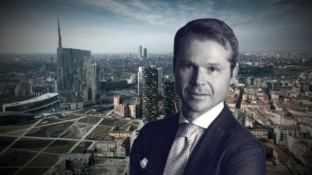 Un uomo in giacca e cravatta, rappresentato in scala di grigi, si trova di fronte a un paesaggio urbano con grattacieli ed edifici moderni sotto un cielo parzialmente nuvoloso.