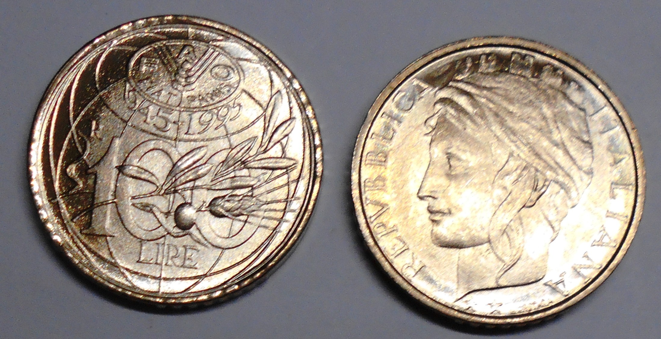 Due monete italiane da 100 lire, una raffigurante un profilo di donna con la scritta "REPVBBLICA ITALIANA", l'altra raffigurante simboli industriali e agricoli con le scritte "1955-1992" e "LIRE".