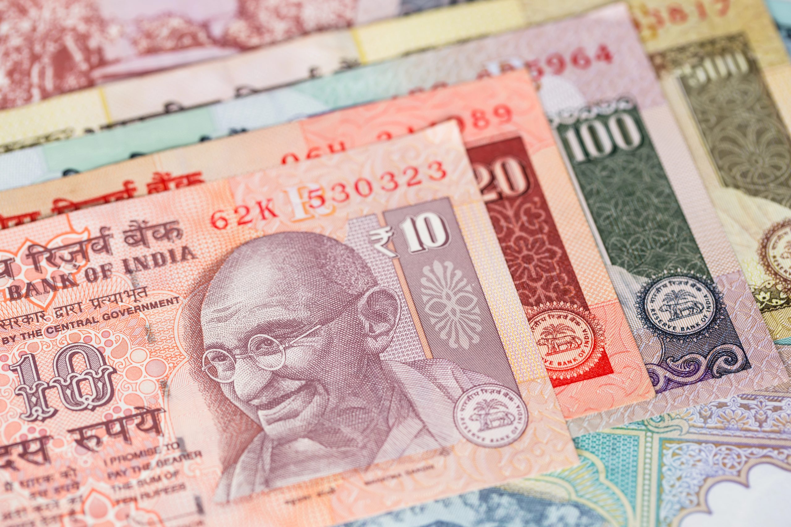 Un primo piano di diverse banconote indiane, tra cui spicca quella da 10 rupie con il ritratto del Mahatma Gandhi, mette in evidenza la vivacità della moneta indiana, simbolo delle sue riforme e degli investimenti che stanno plasmando l'economia del Paese.