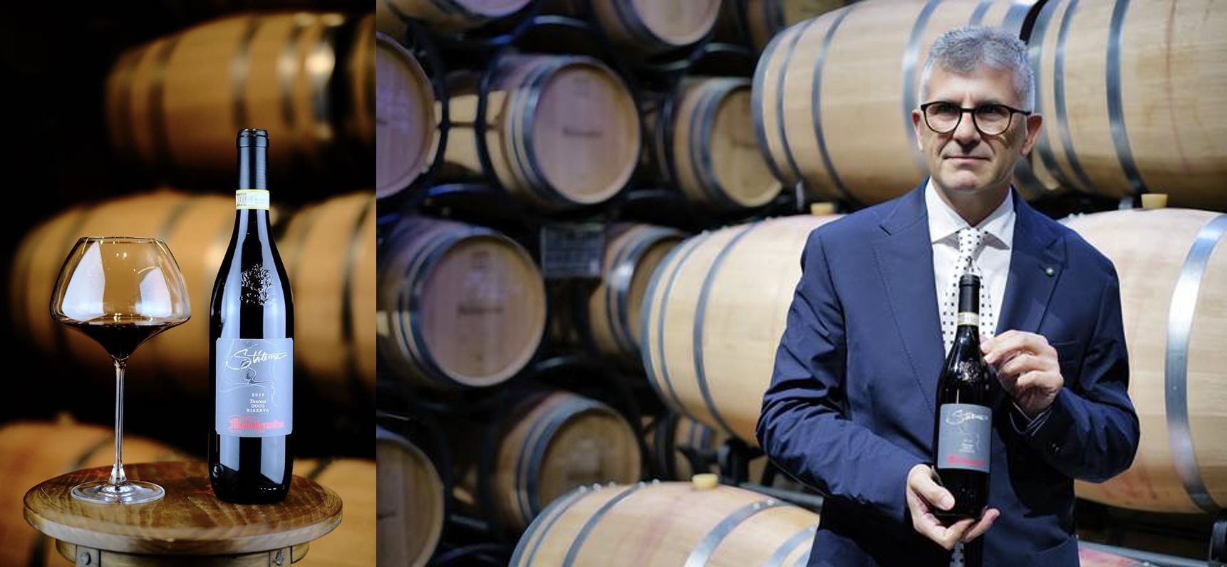 Un uomo in giacca e cravatta tiene in mano una bottiglia di vino rosso in una cantina piena di botti di legno; accanto a lui, un primo piano mostra la stessa bottiglia e un bicchiere di vino rosso su un piccolo tavolo rotondo.
