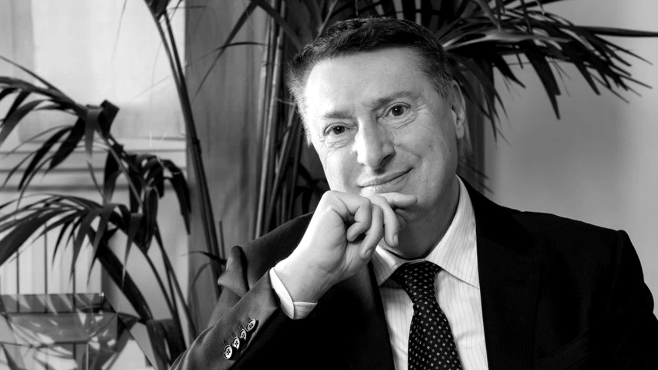 Ritratto in bianco e nero dell’amministratore delegato di una banca, seduto alla scrivania nel suo ufficio, in abito scuro e cravatta.