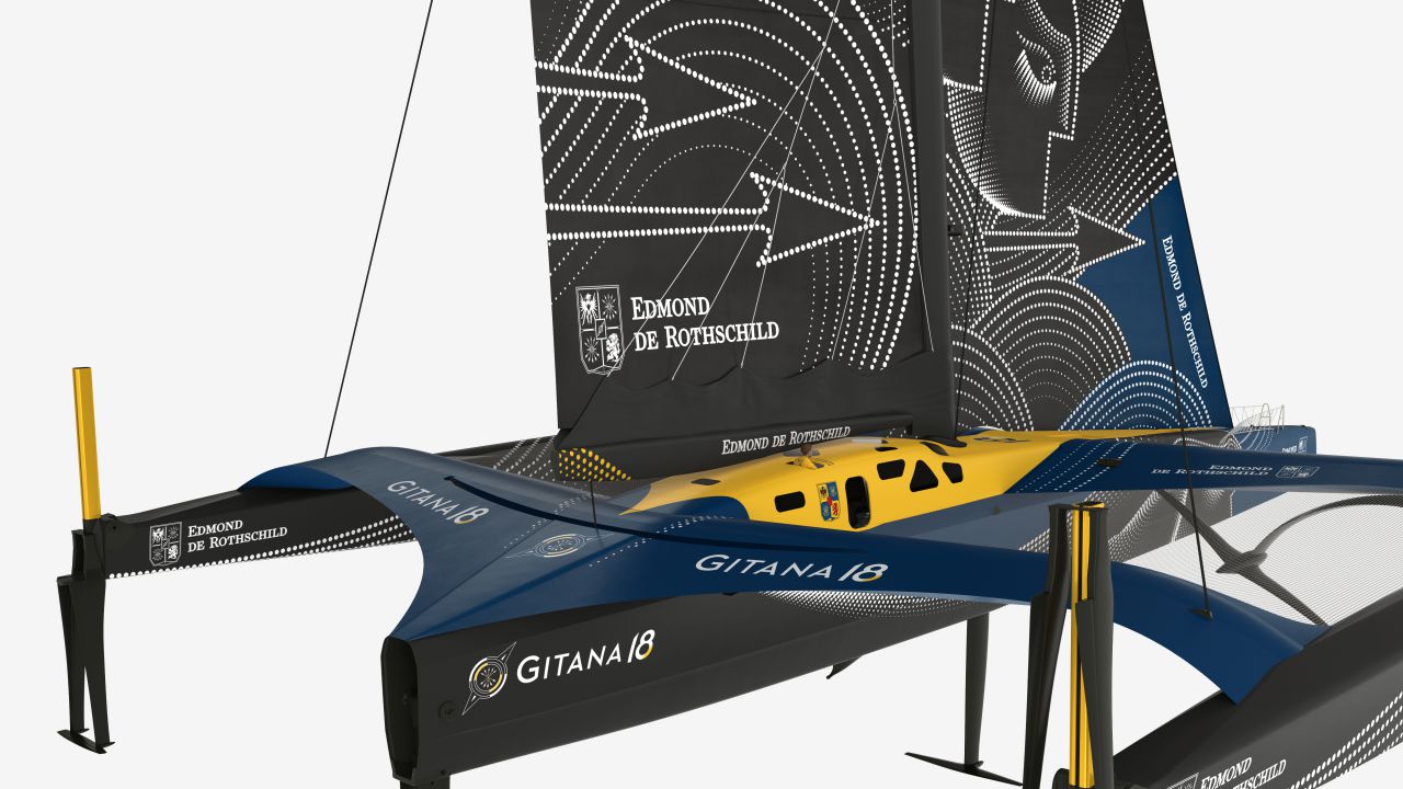 Una moderna barca a vela trimarano da regata blu e gialla denominata "Gitana 18" con disegni aerodinamici e il marchio Edmond de Rothschild sulle vele. La vela è decorata da audaci motivi geometrici e linee.