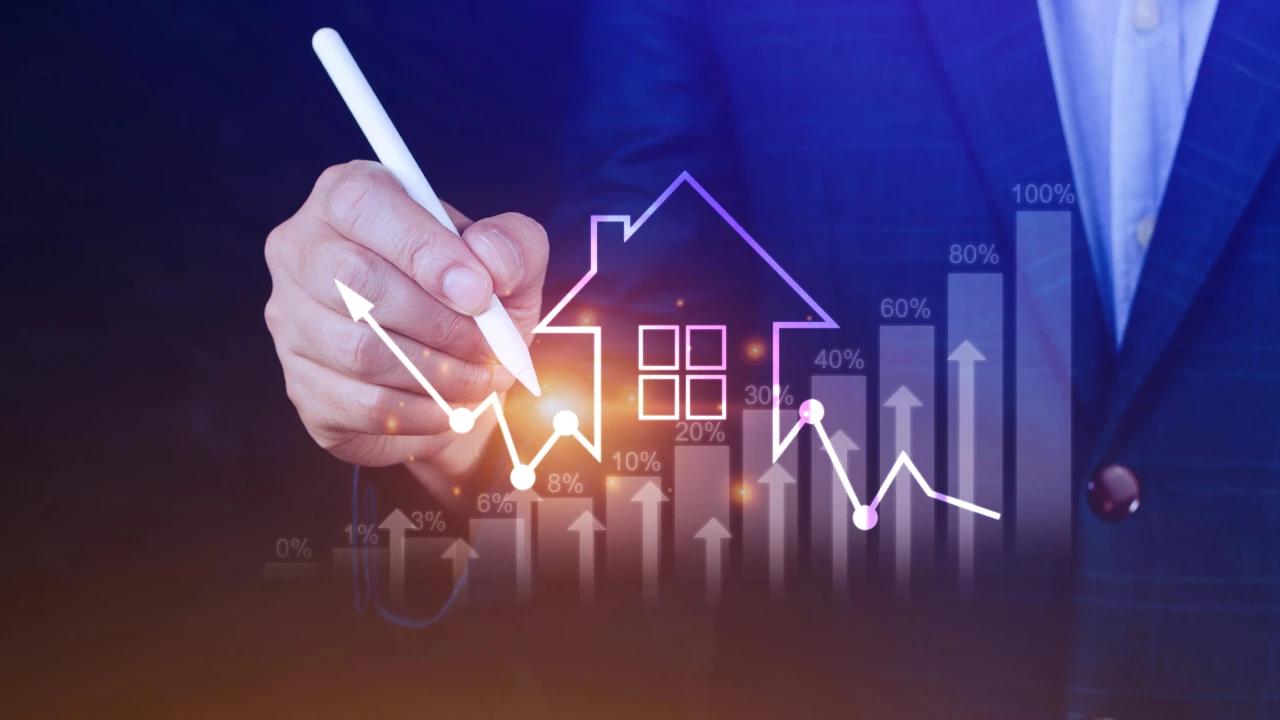 A hand holding a pen draws a rising graph line over a digital house icon, with percentage labels and upward arrows symbolizing real estate growth and investment trends.