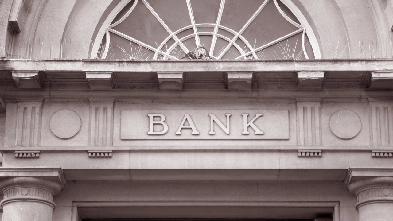 Facciata di una filiale bancaria europea con ingresso chiuso, simbolo della riduzione delle reti fisiche nel settore bancario