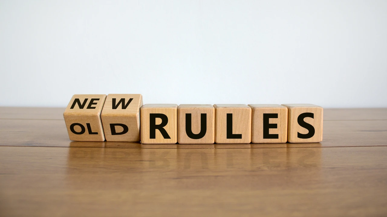 Blocchi di legno su un tavolo scrivono "NEW RULES", con la parola "OLD" parzialmente visibile e barrata, a sottolineare la transizione dalle vecchie alle nuove regole. Lo sfondo è semplice e bianco. Il riferimento va alle novità della riforma su holding di famiglia.