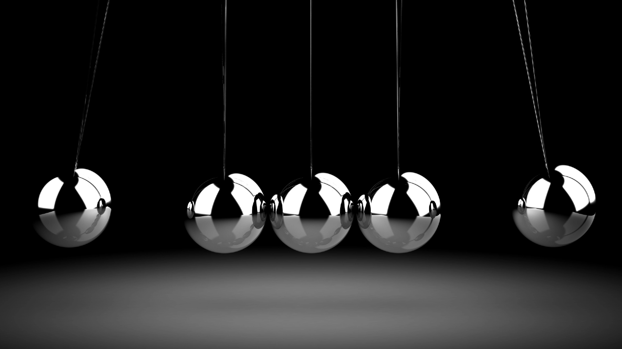 Sfere metalliche di un Newton’s cradle che trasmettono il movimento, metafora dei flussi Etf che influenzano i prezzi azionari