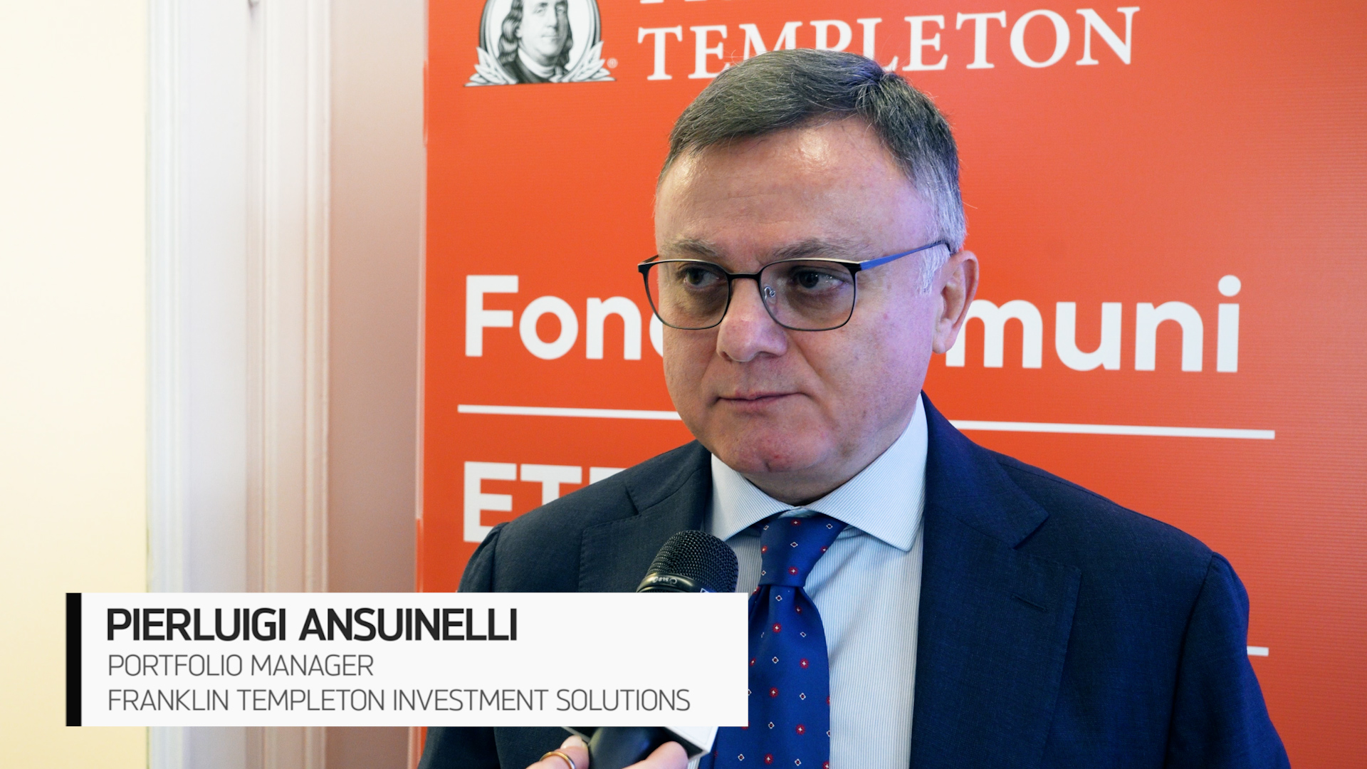 Un uomo in abito e occhiali viene intervistato con un microfono in mano. Alle sue spalle c'è un fondale rosso con il logo e il testo di Franklin Templeton. Il testo sullo schermo lo identifica come Pierluigi Ansuinelli, gestore di portafoglio.