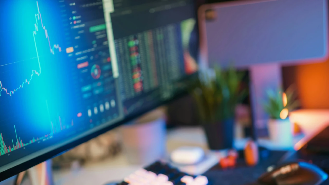 Primo piano di un monitor di computer che visualizza grafici finanziari colorati e dati su debt e titoli, con una tastiera, un mouse e oggetti da ufficio sfocati sullo sfondo. La scena fa pensare al trading azionario o all'analisi del debito con passaggi dal mezzanine al senior.