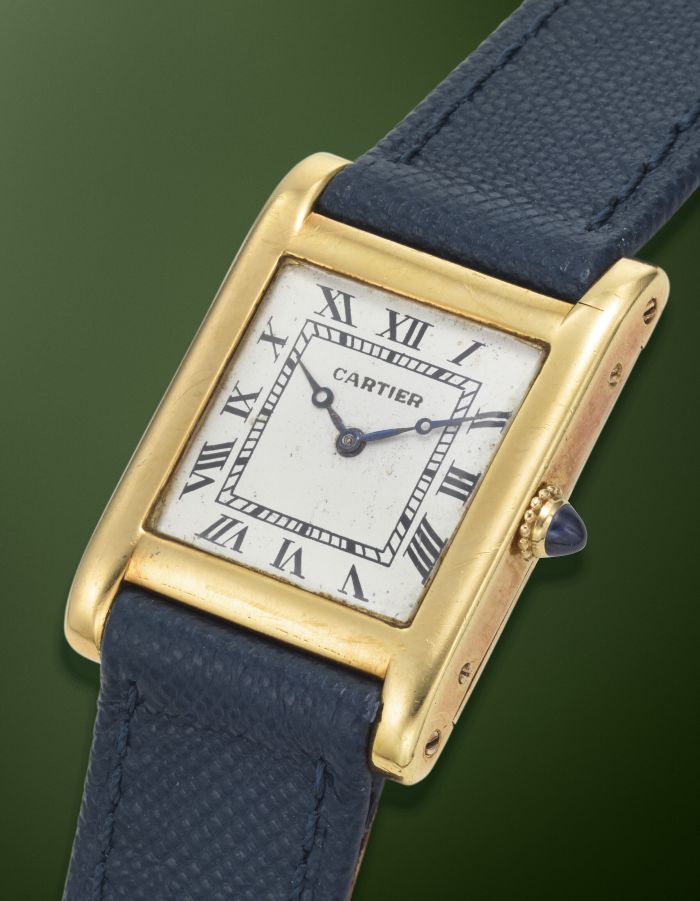 Orologio Cartier vintage con cassa dorata, quadrante bianco con numeri romani e cinturino in pelle blu.
