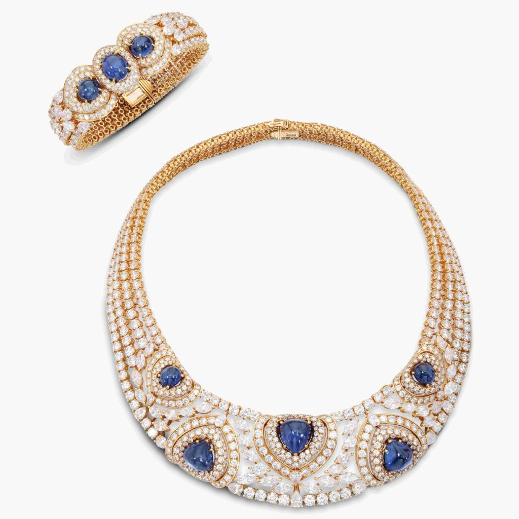 Collezione di gioielli: collana e bracciale in oro con zaffiri blu e diamanti bianchi su sfondo bianco.