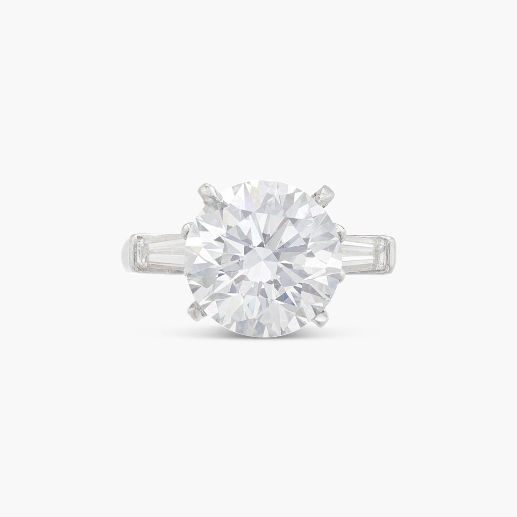 Anello d'argento con grande diamante rotondo centrale e due diamanti rettangolari più piccoli ai lati.