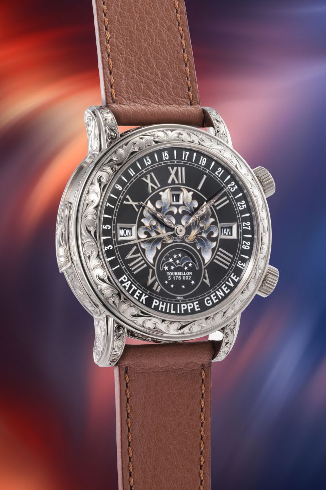 Orologio Patek Philippe con cinturino in pelle marrone, quadrante nero decorato e cassa in metallo lavorato.