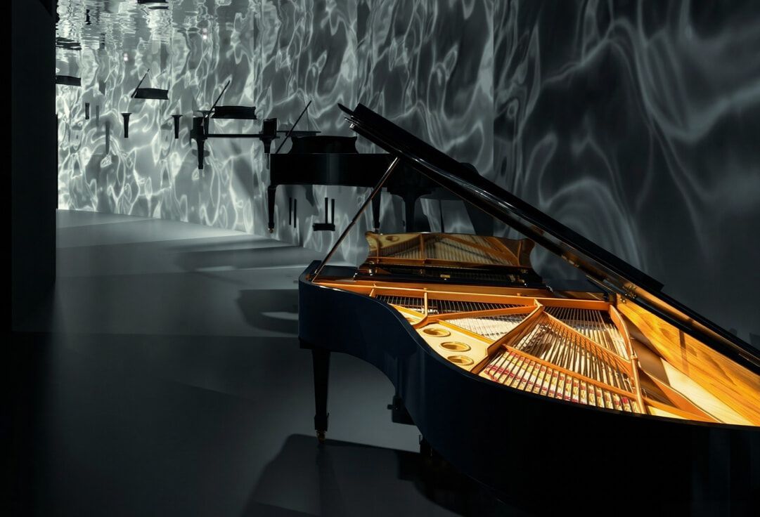 Pianoforte a coda nero aperto in una stanza con riflessi luminosi ondulati sulle pareti.