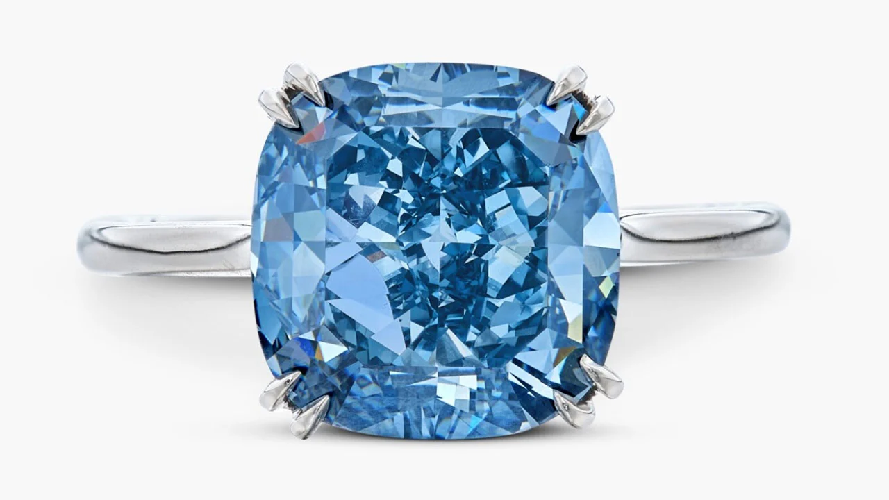 Anello d'argento con grande gemma blu taglio cuscino, montata con quattro griffe. Fondo bianco.