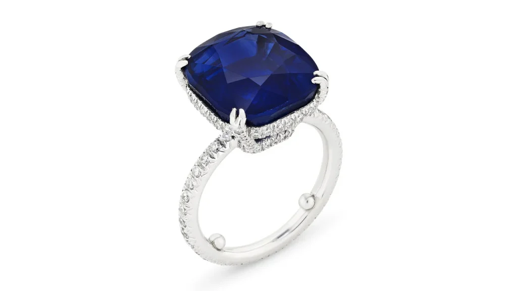 Anello con zaffiro blu a taglio cuscino, contornato da diamanti su montatura in oro bianco.