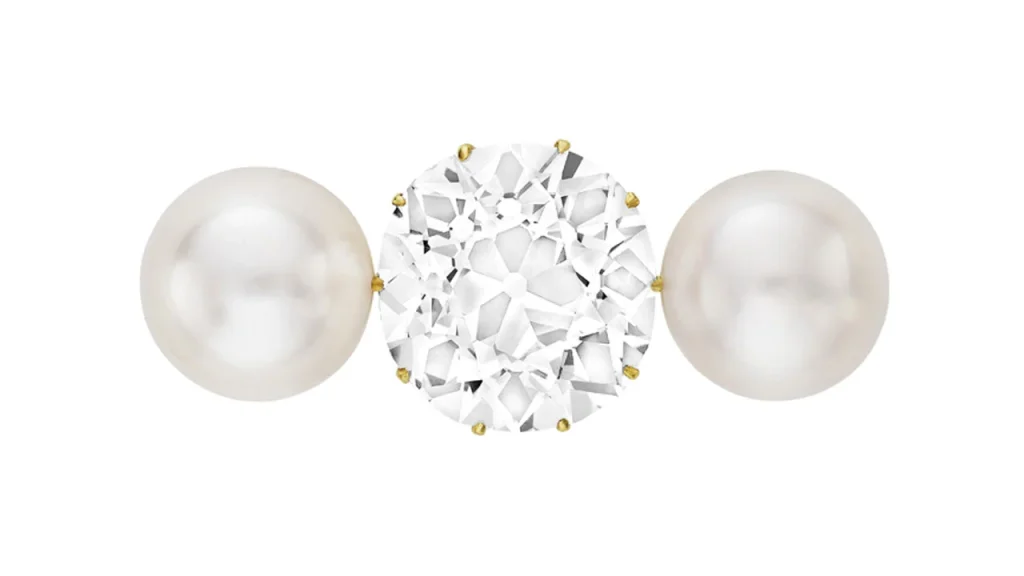 Un diamante rotondo sfaccettato tra due perle bianche rotonde.