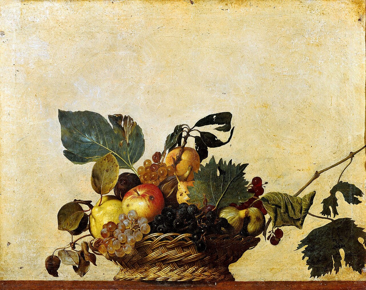 Cesto di vimini traboccante di frutta matura, uva, foglie verdi e rami secchi su sfondo chiaro.