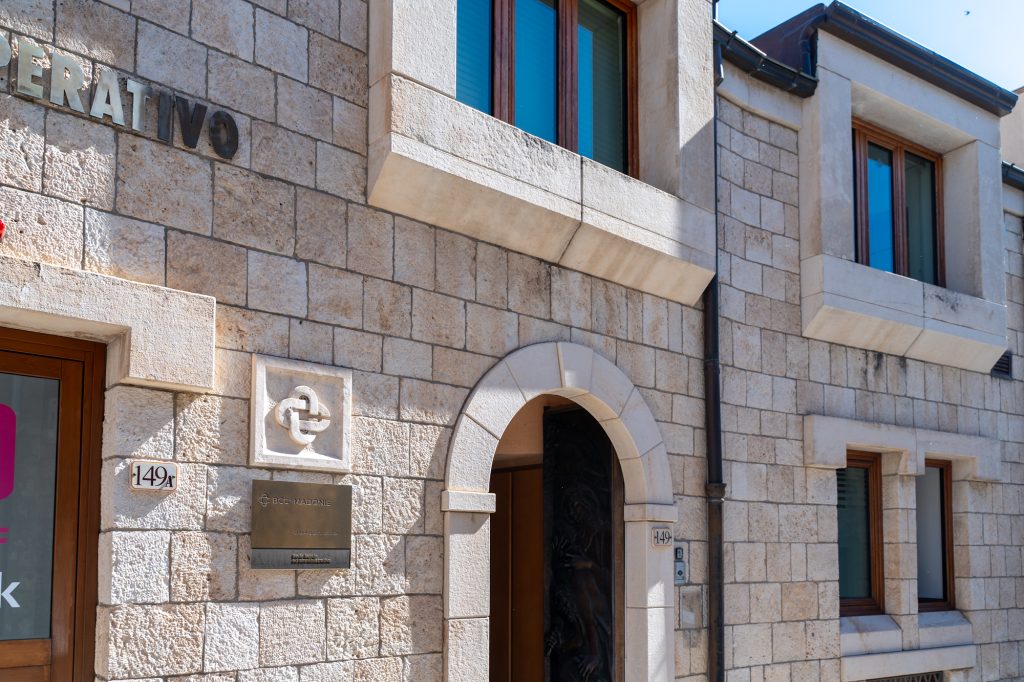 Edificio in pietra con insegne, porta ad arco e finestre.