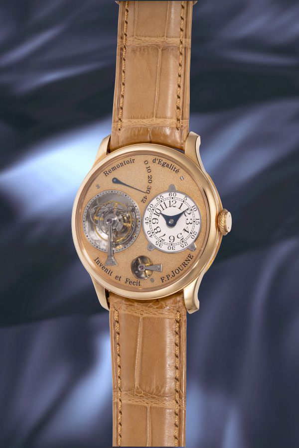 Orologio da polso dorato con cinturino in pelle marrone chiaro, quadrante complesso con meccanismi a vista e numeri arabi.