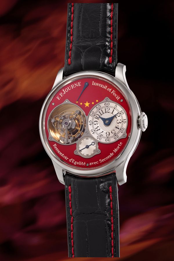 Orologio da polso con cinturino in pelle nera e cuciture rosse, quadrante rosso con dettagli dorati e meccanismi a vista.