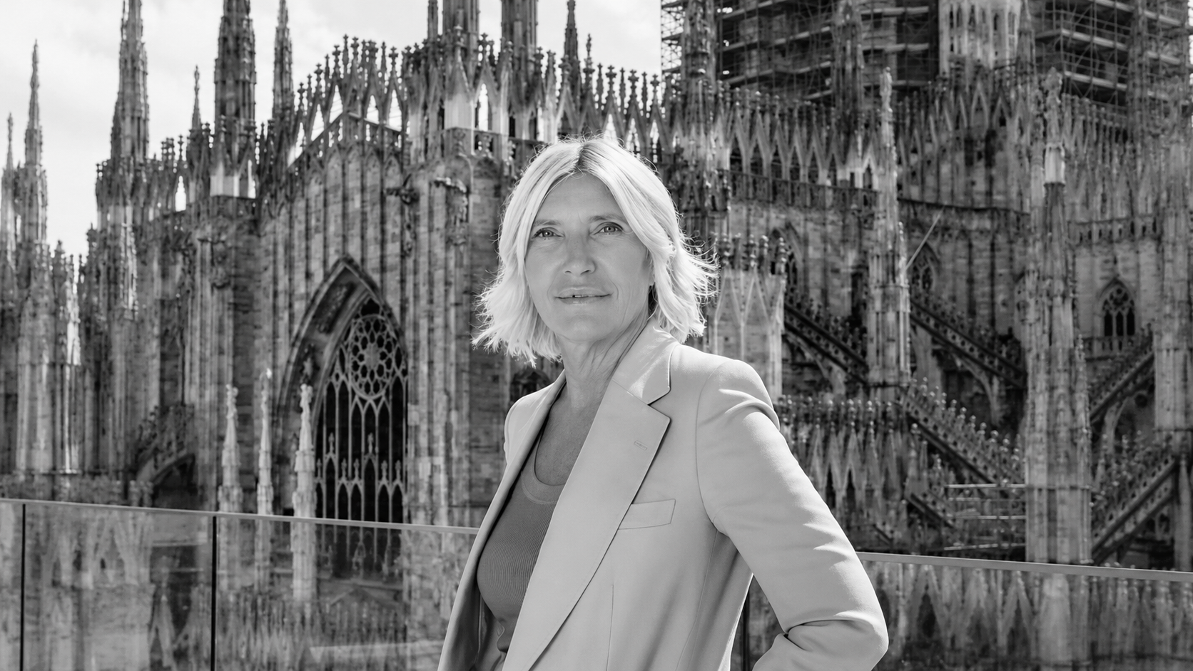 Donna bionda in giacca con il Duomo di Milano sullo sfondo.