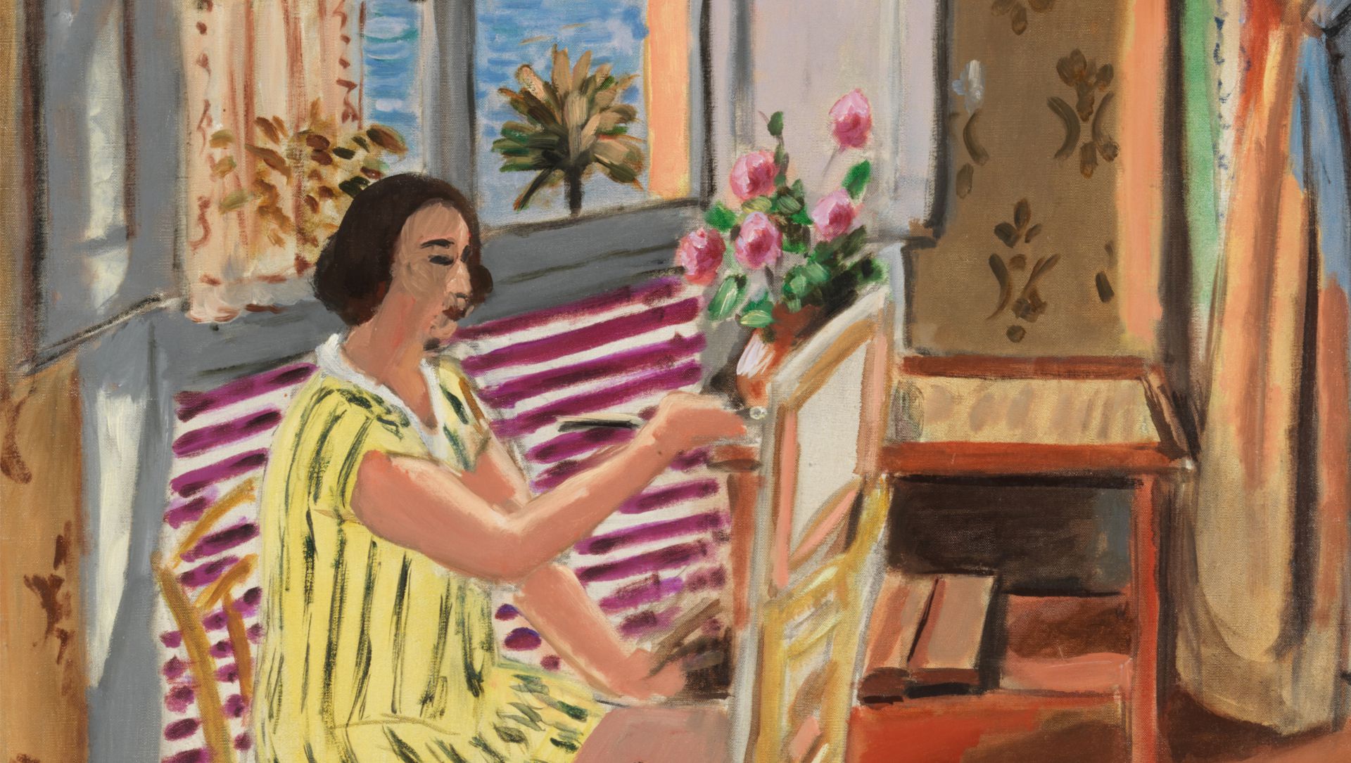 Donna con vestito giallo a righe dipinge un quadro, fiori rosa su un tavolo.