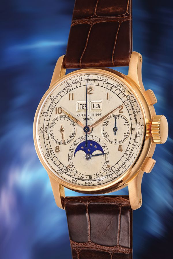 Orologio Patek Philippe in oro giallo con quadrante bianco, fasi lunari e cinturino in pelle marrone.