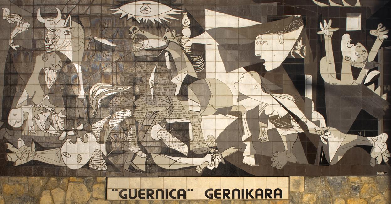Mural in bianco e nero con figure umane e animali stilizzati, con la scritta "Guernica Gernikara".