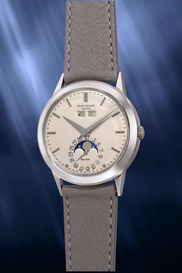 Orologio Patek Philippe Geneve con cinturino grigio, quadrante bianco, indicatore giorno e data, e fasi lunari.