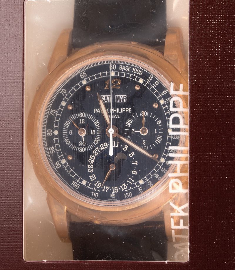 Orologio Patek Philippe con cinturino nero, quadrante blu scuro con numeri e lancette dorate, confezionato in scatola marrone.