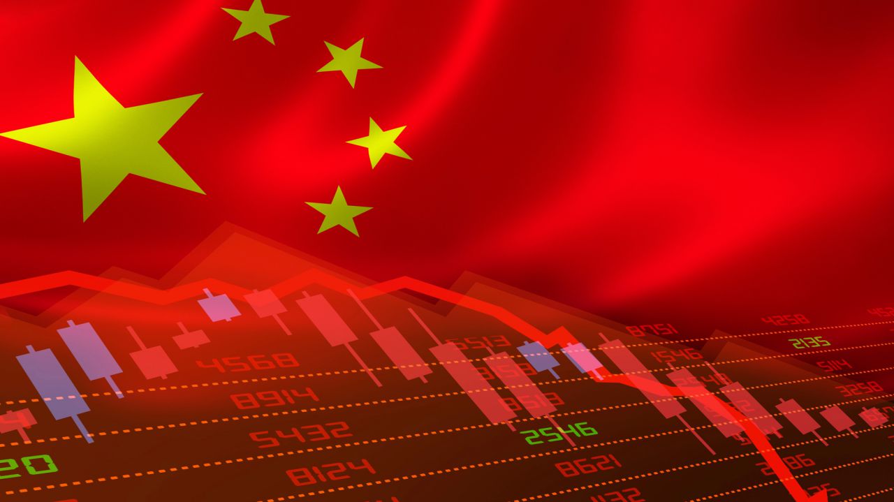 Bandiera cinese con grafico finanziario in calo e candele rosse e viola.