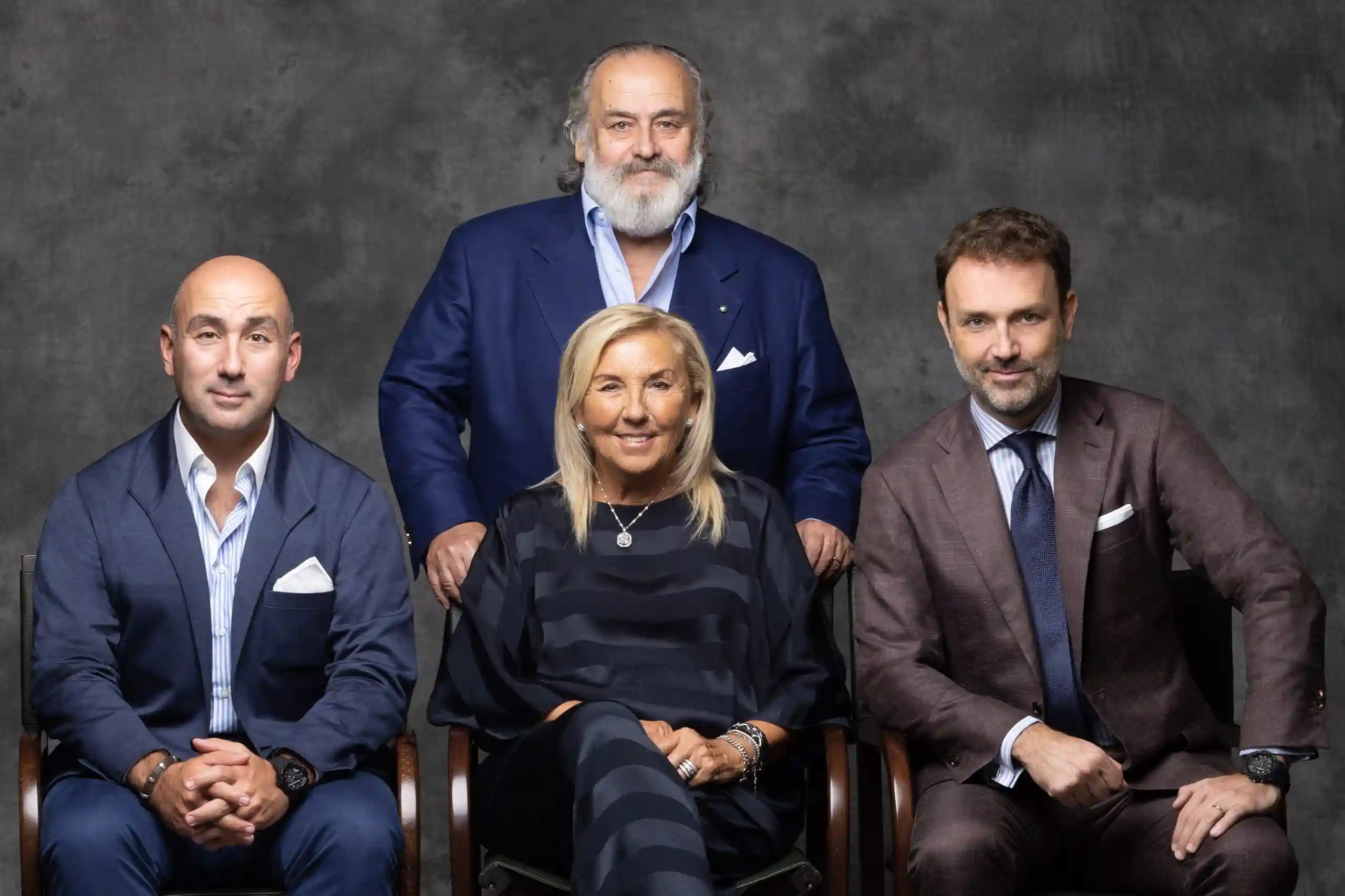 Quattro persone in abiti eleganti posano sedute e in piedi.
