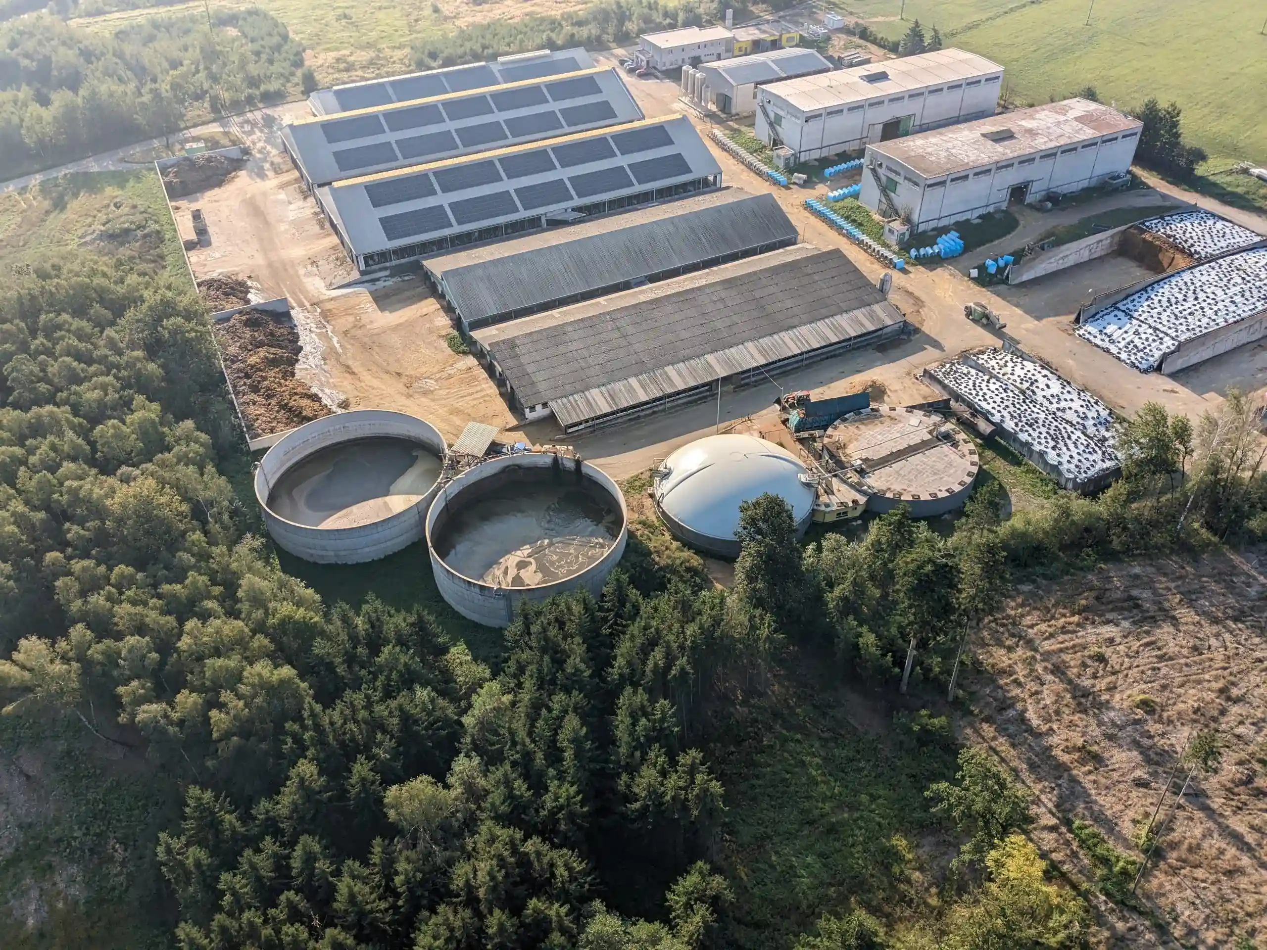 Edificio con pannelli solari, vasche, biodigestore e balle coperte.