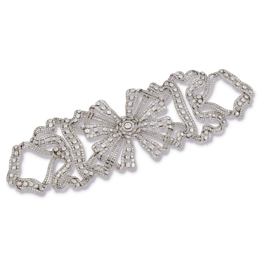 Bracciale in platino e diamanti con fiocco centrale e motivi a nastro ondulato.