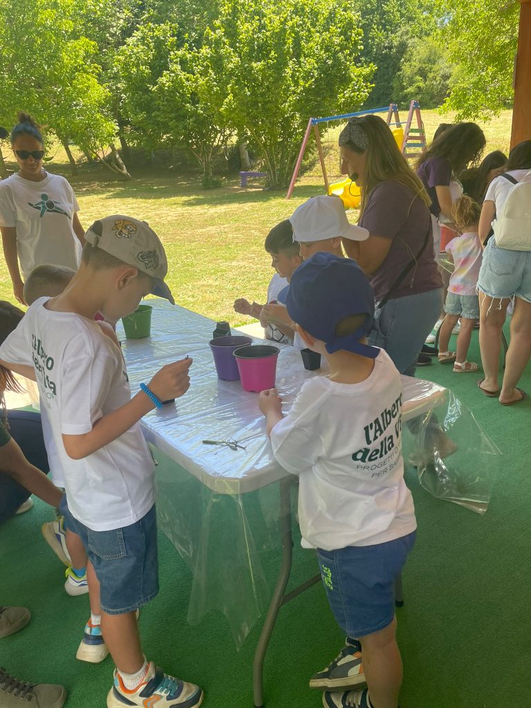 Bambini e adulti partecipano a un'attività all'aperto con vasi e piante.