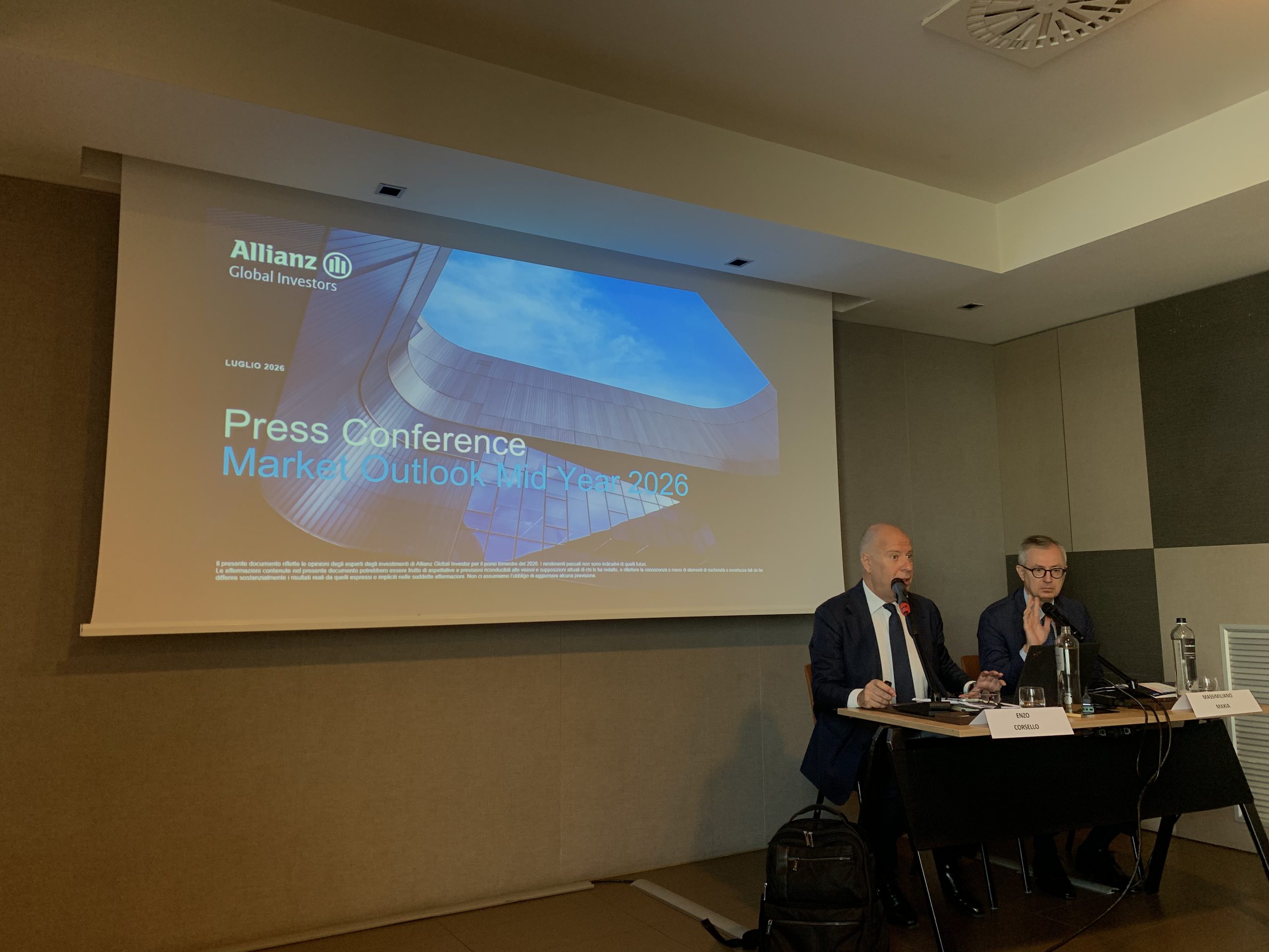 Due uomini parlano a una conferenza stampa con uno schermo che mostra Allianz Global Investors.