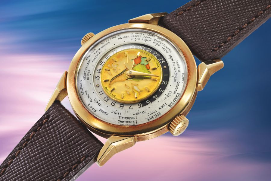 Orologio da polso in oro con quadrante a mappa del mondo e cinturino in pelle marrone.