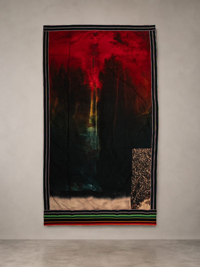 Tessuto con macchie rosse, gialle e nere, bordi a righe colorate e un rettangolo texturizzato.