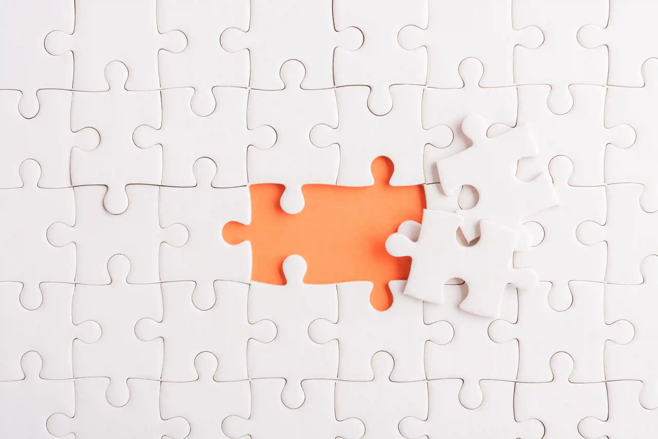 Pezzi di puzzle bianchi con un'area arancione vuota e pezzi sciolti.