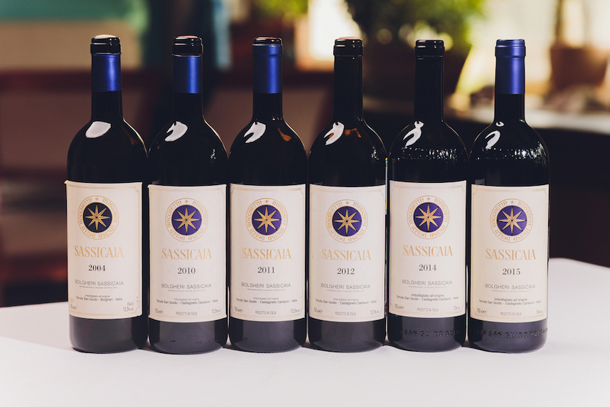 Sei bottiglie di vino Sassicaia con etichette che indicano gli anni 2004, 2010, 2011, 2012, 2014, 2015.