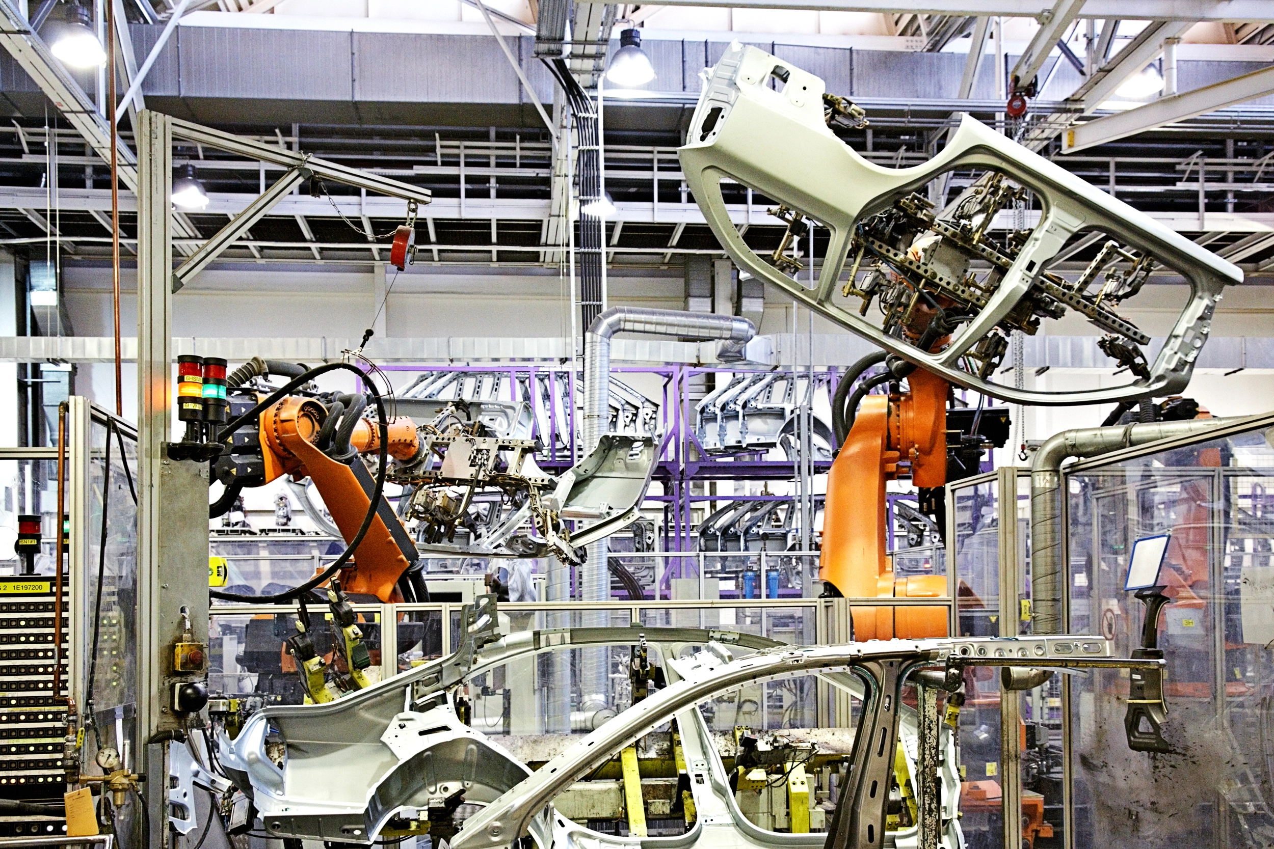 Fabbrica di automobili con bracci robotici che assemblano telai di auto.