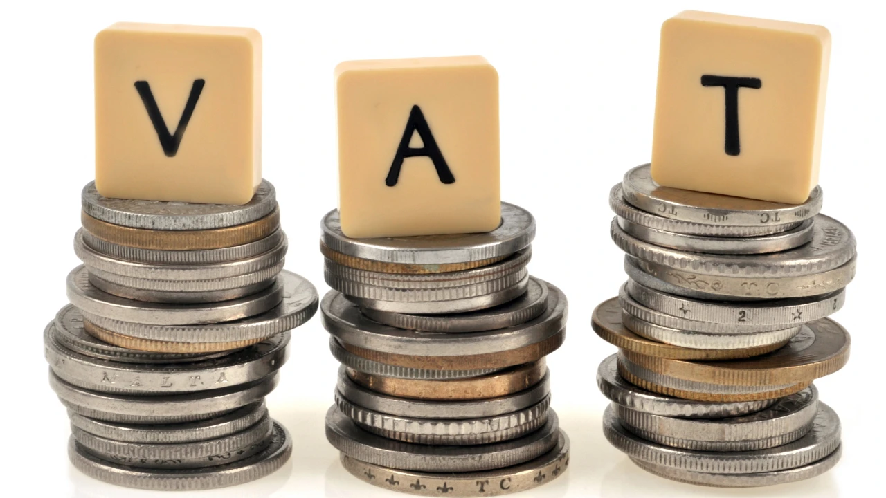 Tre pile di monete con lettere che formano "VAT" in cima.