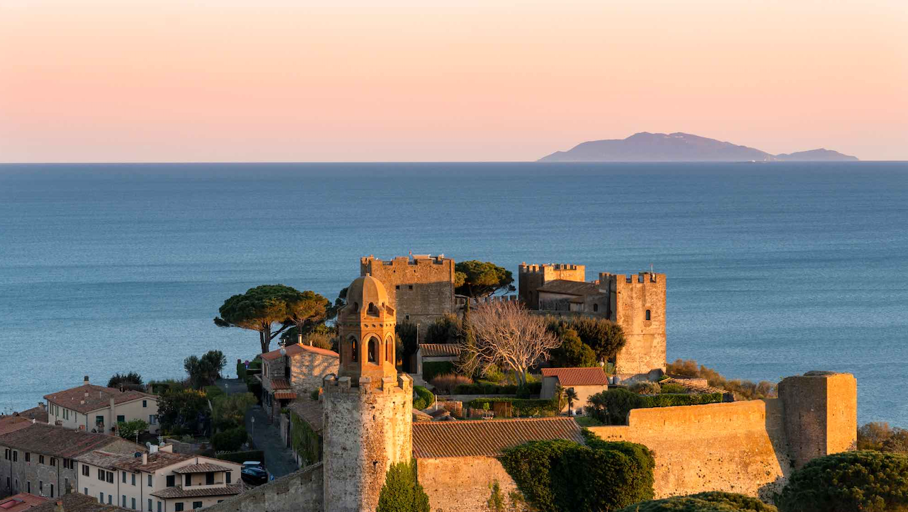 Castello medievale su una collina con vista sul mare e isole all'orizzonte.