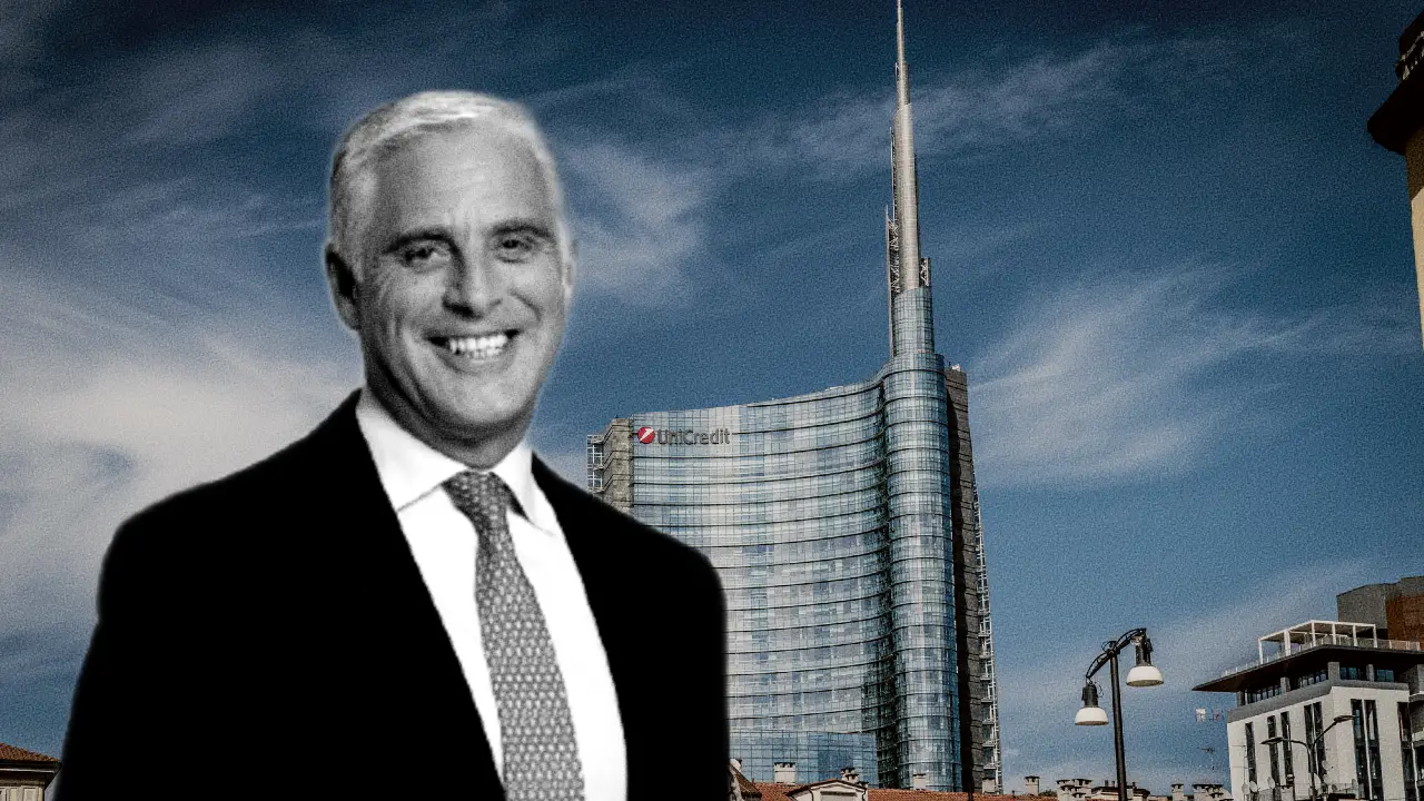 Uomo in abito scuro sorride davanti a un grattacielo moderno con logo UniCredit.