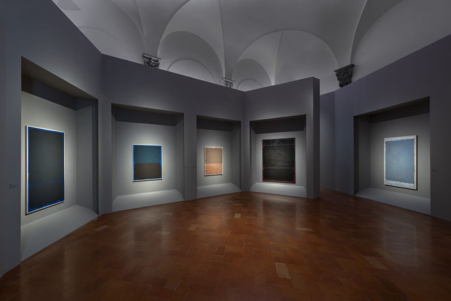 Opere astratte su tela in una galleria d'arte con soffitto a volta e pavimento in cotto.