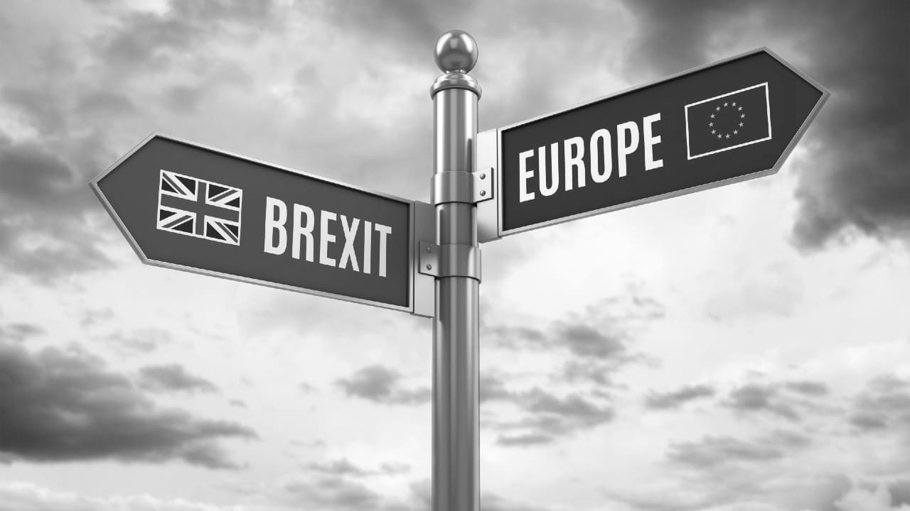 Cartello stradale con frecce per "BREXIT" (bandiera UK) e "EUROPE" (bandiera UE).